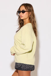 Woman wearing a light yellow sweater and black shorts with white polka dots against a white background