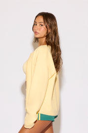 Woman wearing a light yellow sweatshirt and green shorts on a white background