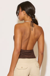 Woman wearing a brown halter top with open back against a white background