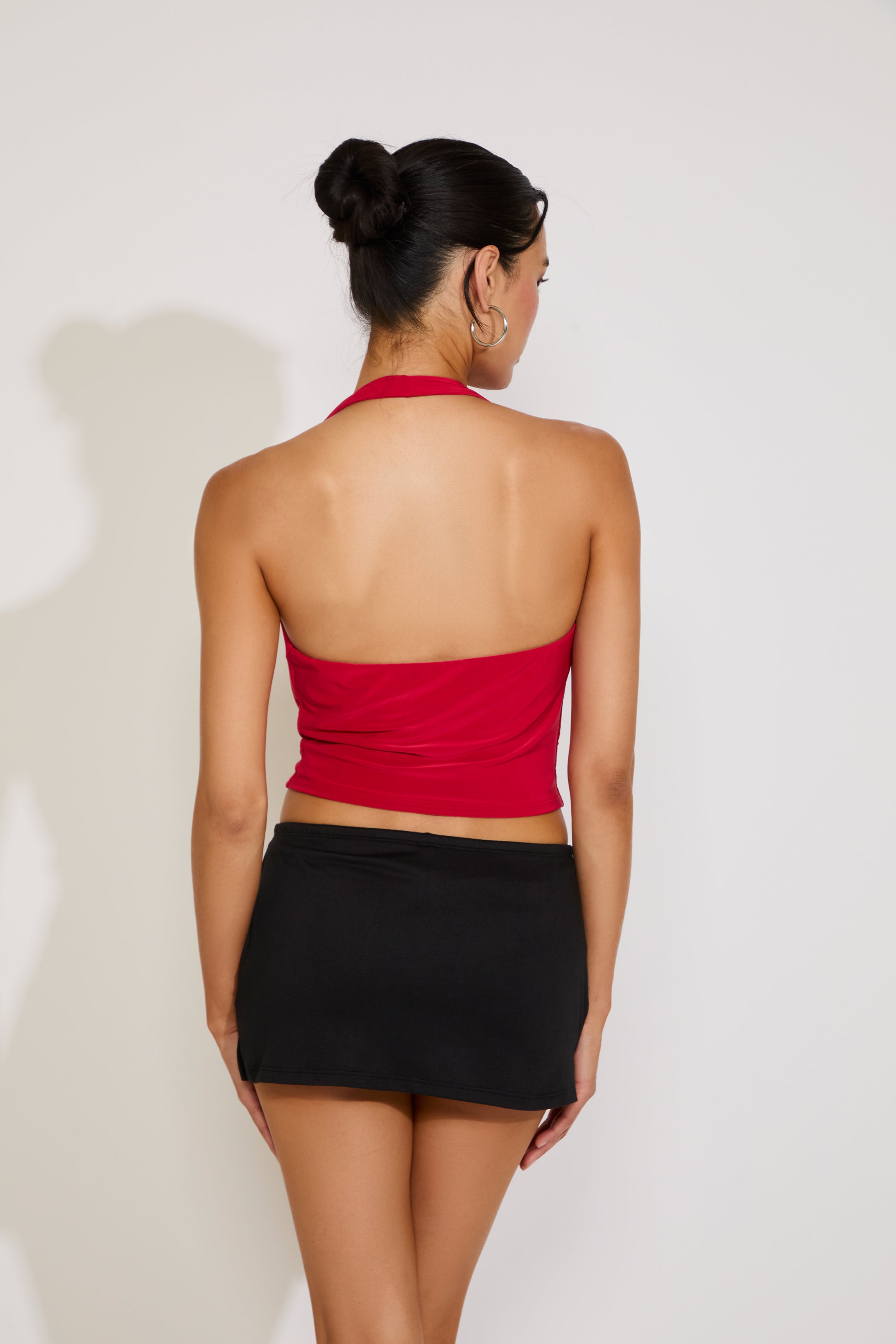 Woman wearing a red halter top and black skirt on a white background