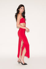 Woman wearing a red dress with a slit on a white background