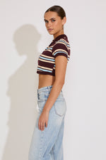 Woman wearing a striped crop top and light blue jeans against a white background