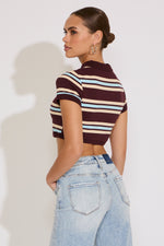 Woman wearing a striped crop top and jeans against a white background