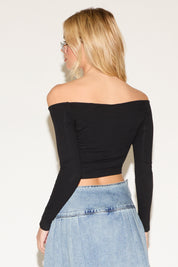 Woman in a chic off-the-shoulder black top and a denim skirt. 