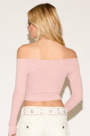 Woman in a chic off-the-shoulder pink top and white jeans. 