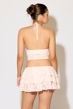 Woman wearing a light pink lace two-piece set against a white background