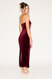 Woman wearing a burgundy strapless dress on a white background