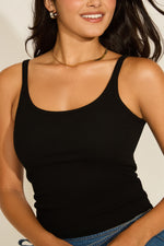 A woman wearing a black crew neck ribbed trim tunic tank top with a classic crew neck and a fitted silhouette.