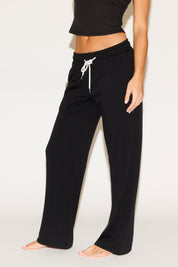 Person wearing black drawstring pants on a white background