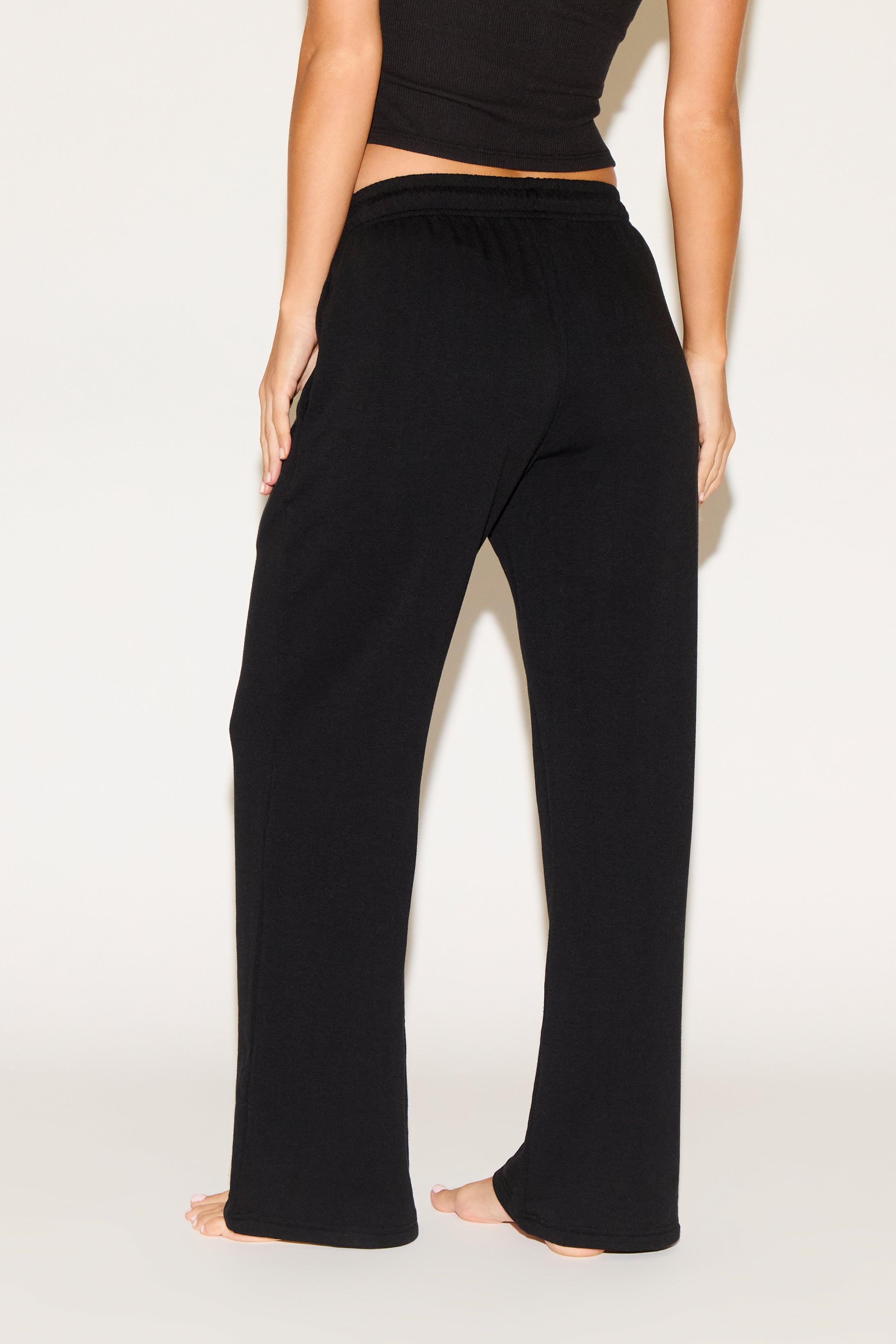 Person wearing black wide-leg pants on a white background