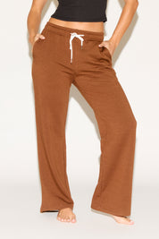 Person wearing brown wide-leg pants on a white background