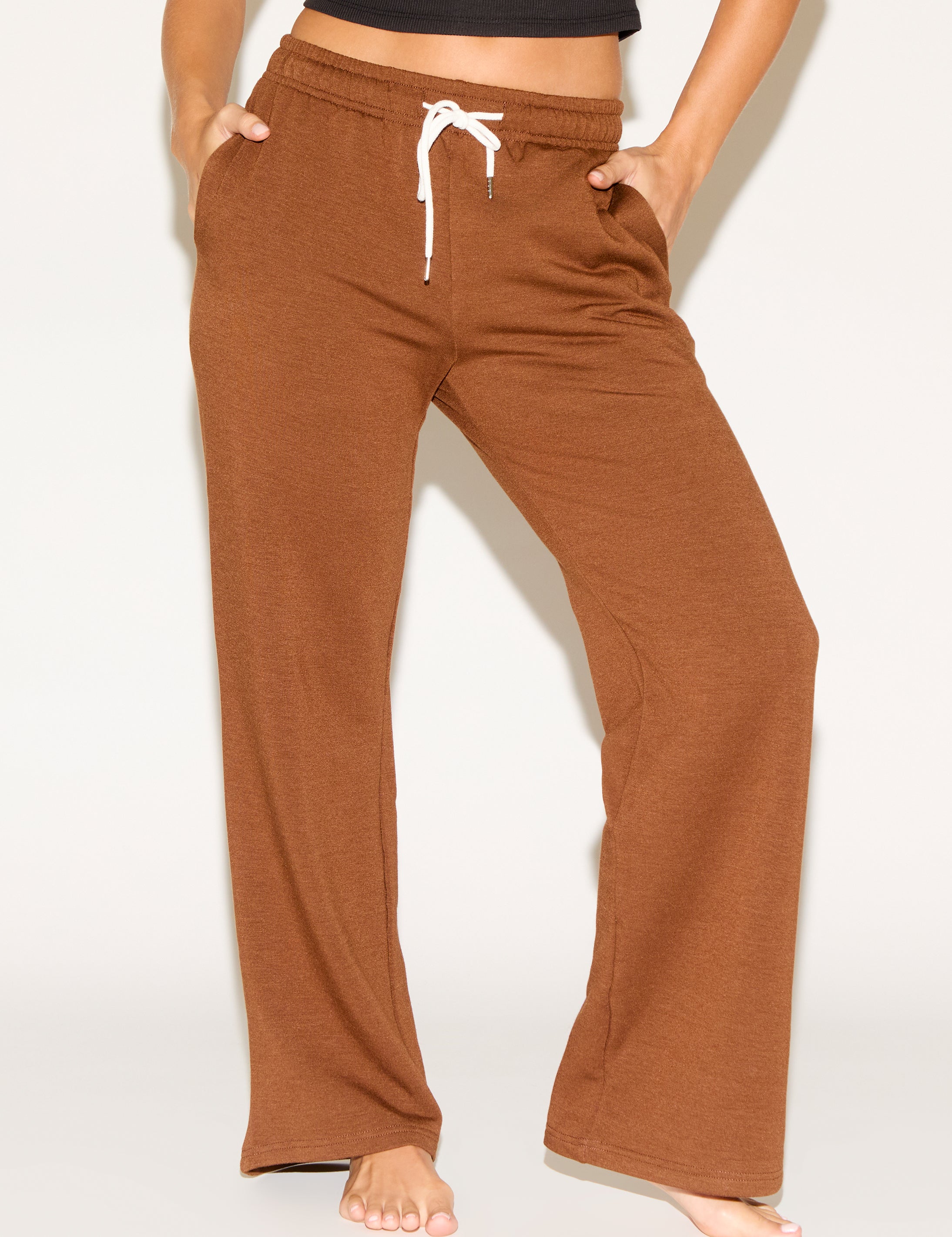 Person wearing brown wide-leg pants on a white background