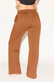 Brown sweatpants worn by a person on a white background