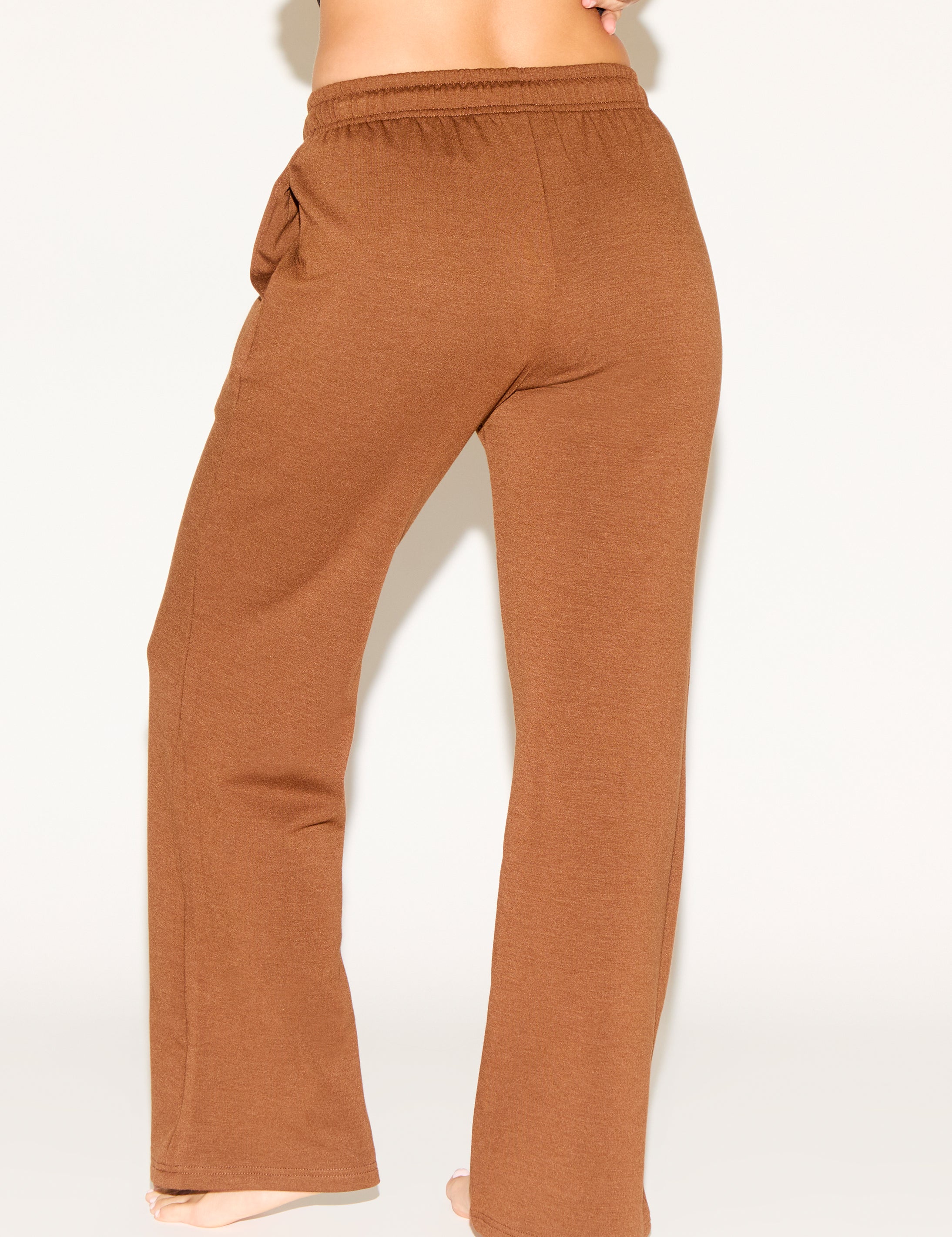 Brown sweatpants worn by a person on a white background