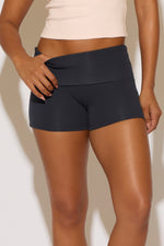 Person wearing black athletic shorts on a plain background