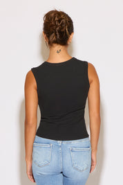 Person wearing a black sleeveless top and blue jeans against a white background