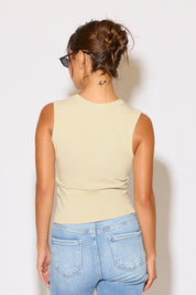 Person wearing a light green sleeveless top and blue jeans against a white background