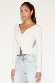 Woman wearing a white long-sleeve top and light blue jeans on a white background