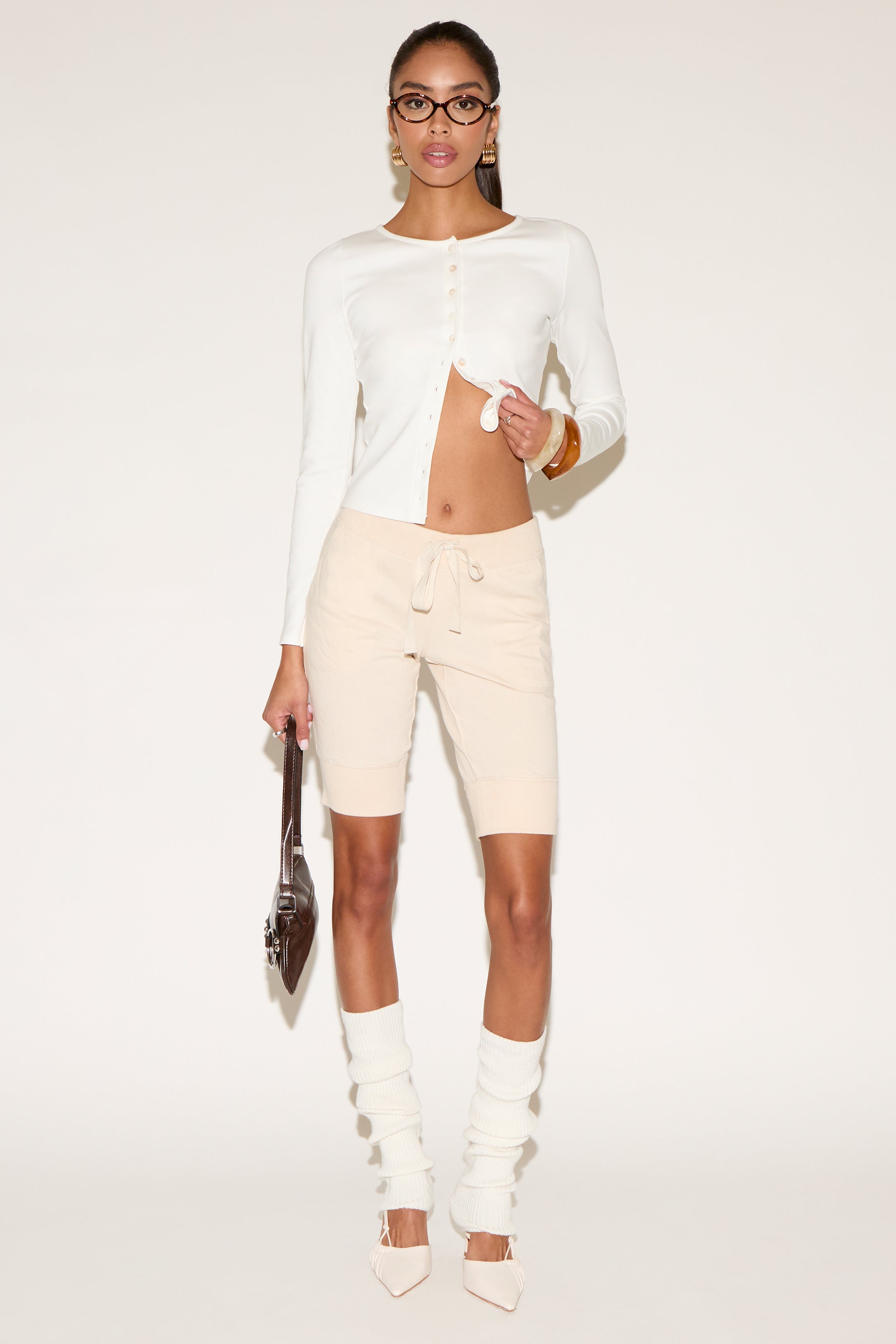 Woman wearing a white outfit with beige riding pants on a white background