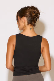 Woman wearing a black tank top against a white background