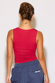 Person wearing a red tank top and blue pants with a visible brand logo on a white background