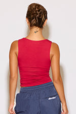 Person wearing a red tank top and blue pants with a visible brand logo on a white background