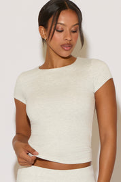 Woman wearing a white short-sleeve top against a plain background