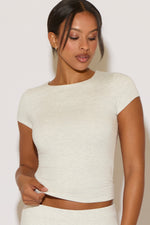 Woman wearing a white short-sleeve top against a plain background