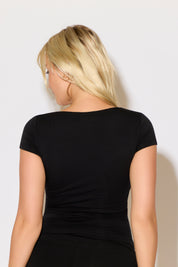 Model is wearing a black square neck slim fit cap sleeve top with black shorts.