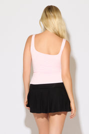 Model is wearing a pink scoop neck cropped rayon tank top with a heather grey skirt on a white background.