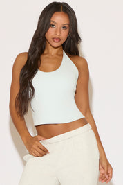 Woman wearing a white halter top and pants against a light background