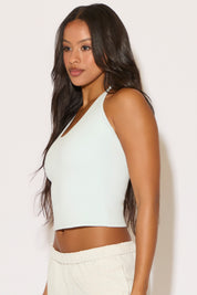 Woman wearing a light green halter top against a white background