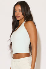 Woman wearing a light green halter top against a white background