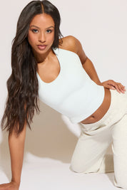 Woman wearing a white bodysuit and pants against a plain background