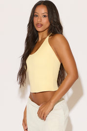 Woman wearing a yellow halter top against a white background