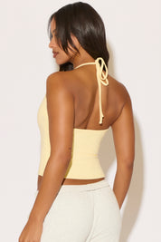 Woman wearing a yellow halter top against a white background