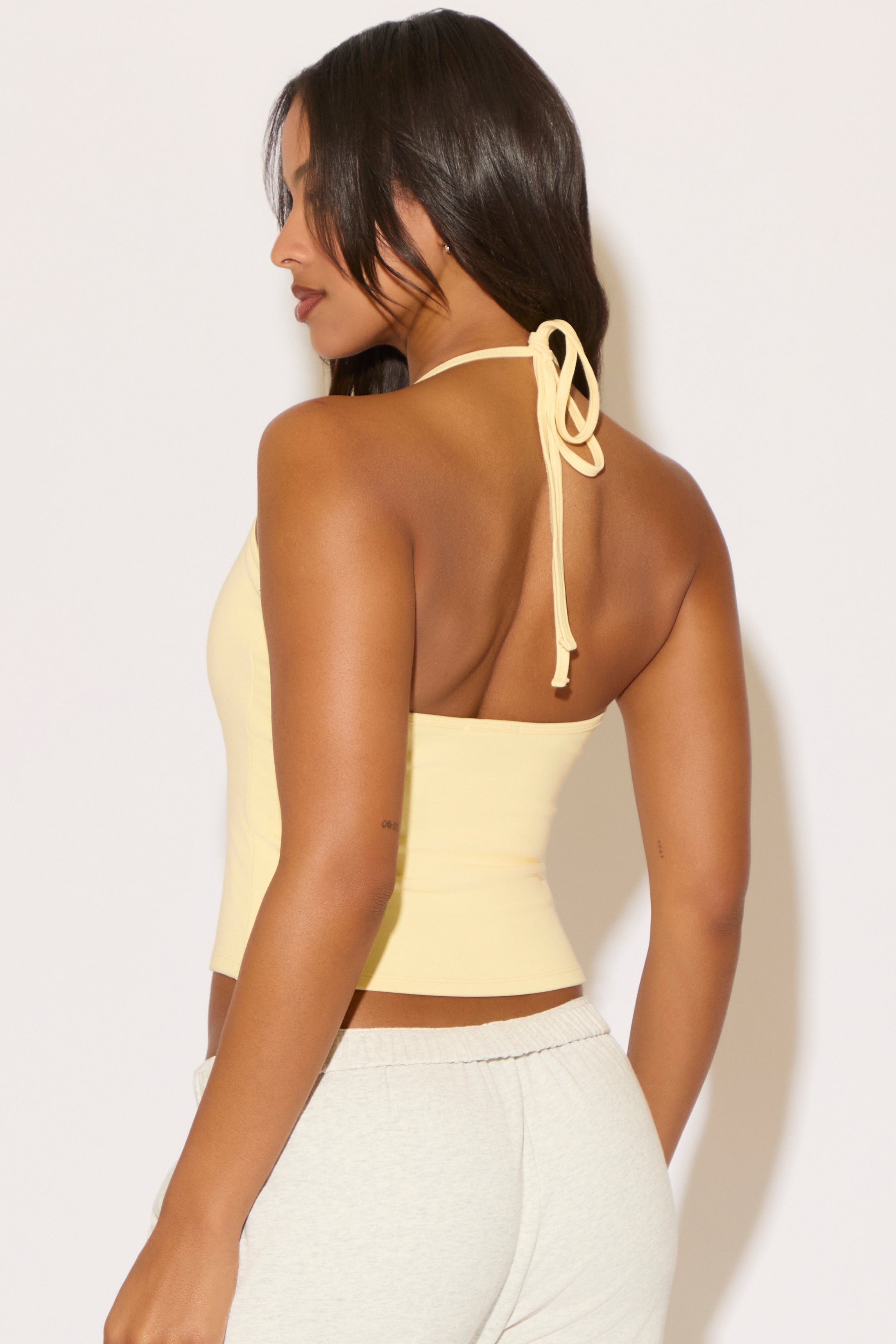 Woman wearing a yellow halter top against a white background