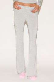 Model wearing grey low-rise flare pants with a fold-over waistband, styled with a grey long-sleeve top and pink socks against a neutral background.