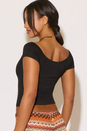 Woman wearing a black top with a patterned skirt against a white background