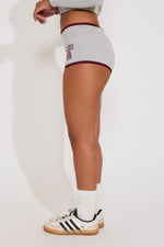 Person wearing gray athletic shorts with maroon text on a white background