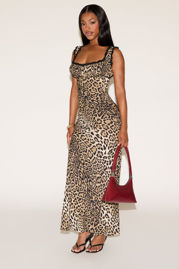 Woman wearing a leopard print dress with a red handbag on a white background