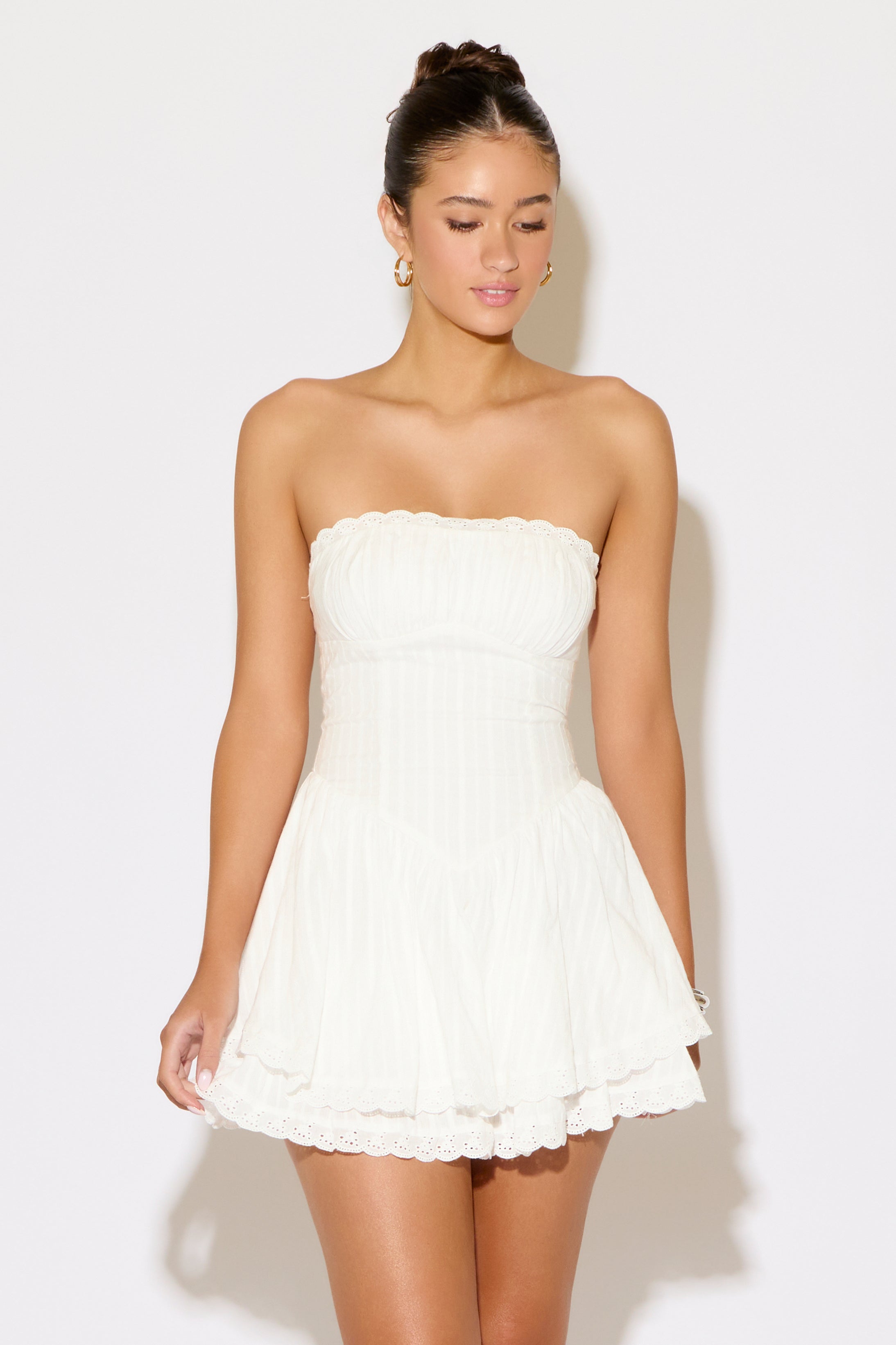 Woman wearing a white strapless dress against a plain background