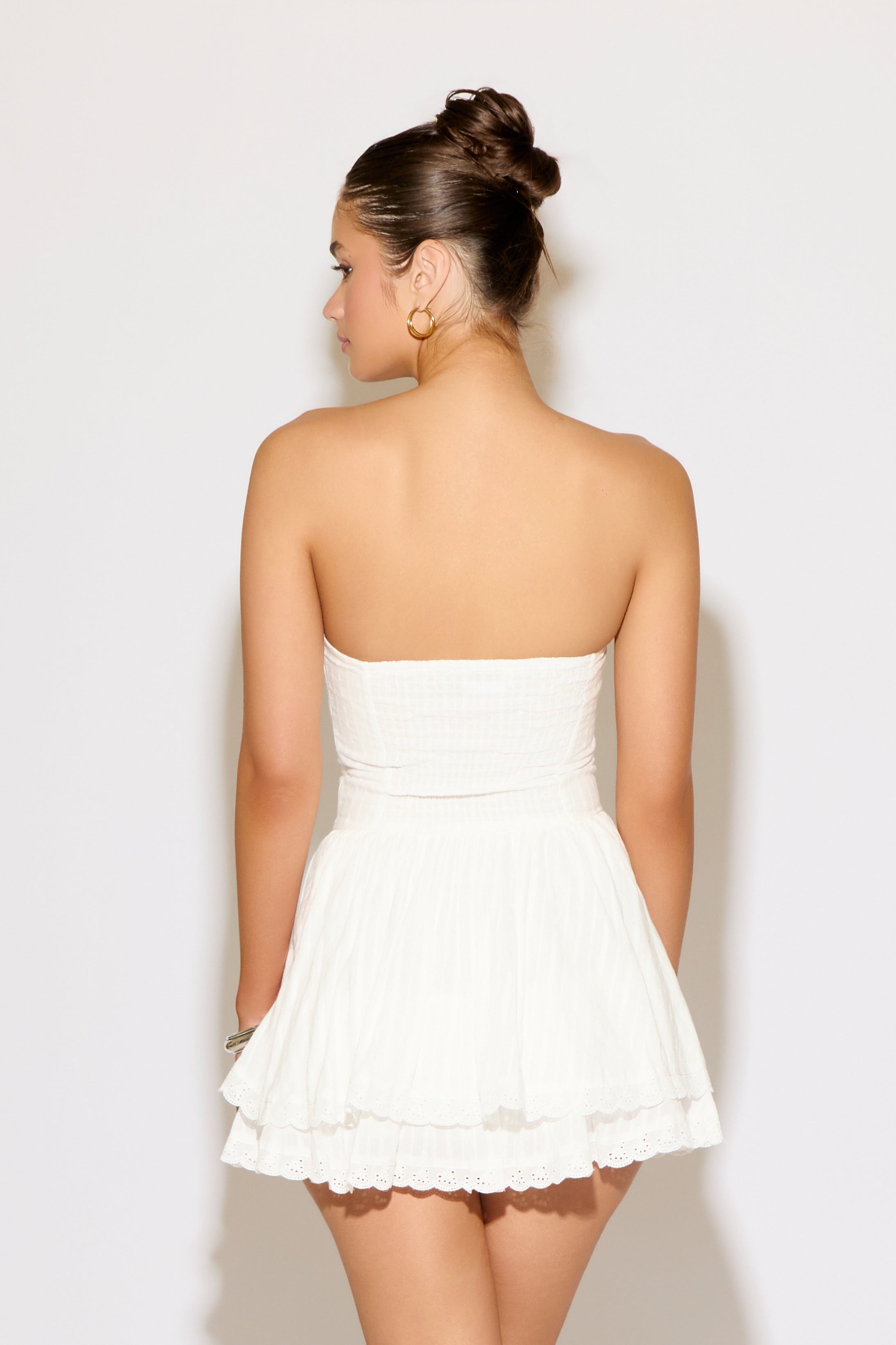 Woman wearing a white strapless dress against a plain background