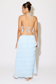 Woman wearing a light blue sarong with a white top against a white background