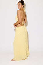 Woman wearing a yellow strapless top and long skirt against a white background