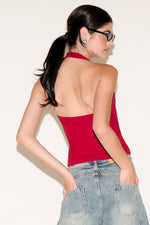 Woman wearing a red halter top and blue jeans against a white background