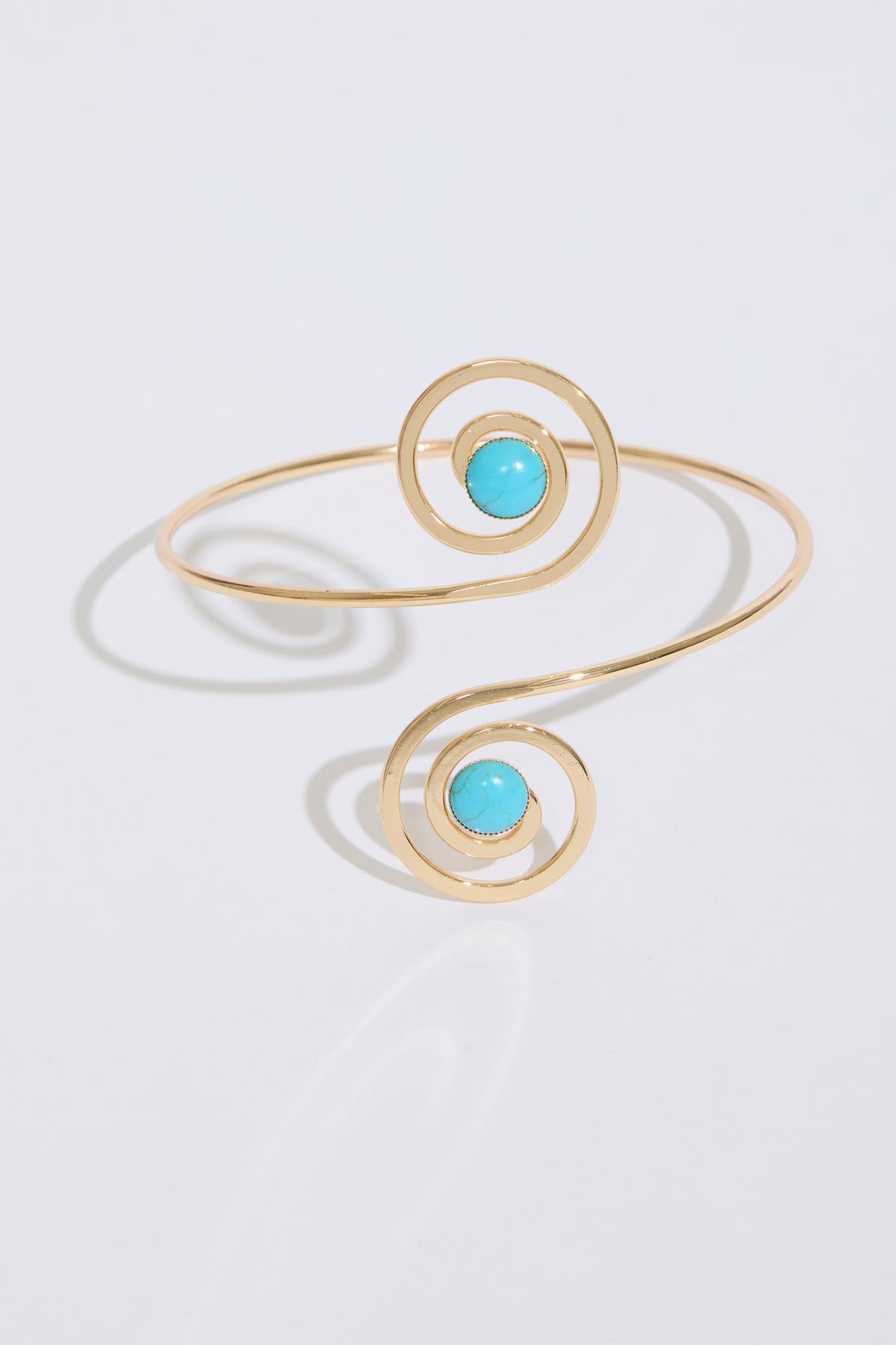 Model is wearing a SWIRLS WITH JEWELS METAL ARM CUFF with a blue dress on a white background.