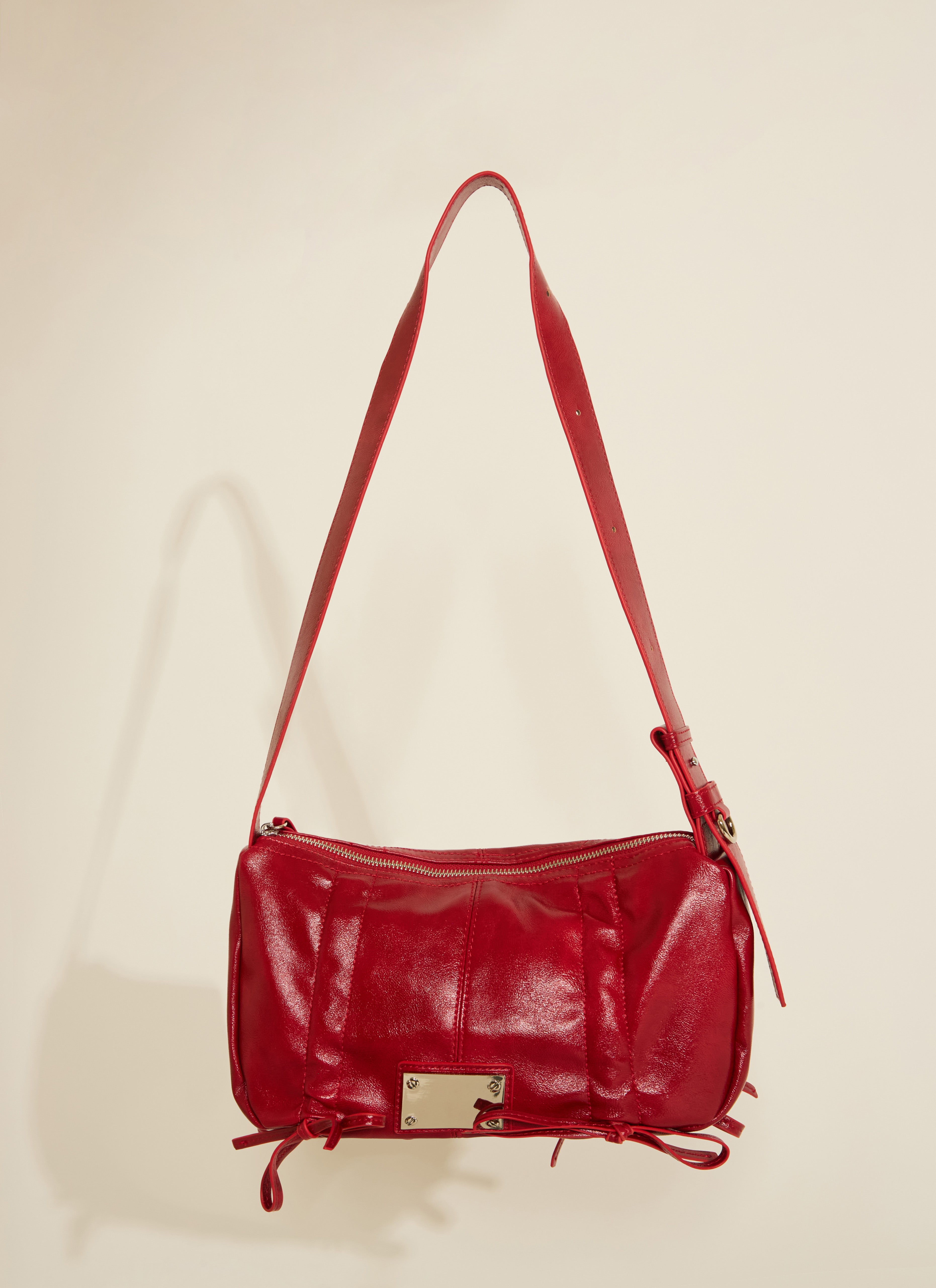 A red vegan leather handbag with scrunch tie details and silver hardware, displayed against a neutral background.