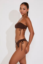 Woman wearing a brown bikini against a white background