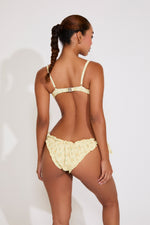Woman wearing a yellow bikini against a white background